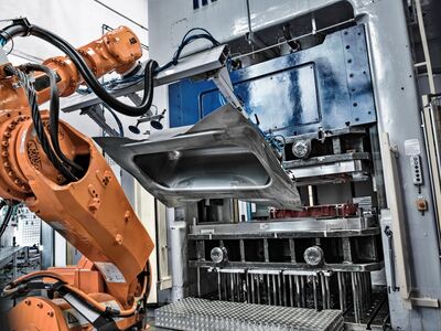 Der Roboter zieht eine tiefgepresste Wanne aus der Form.