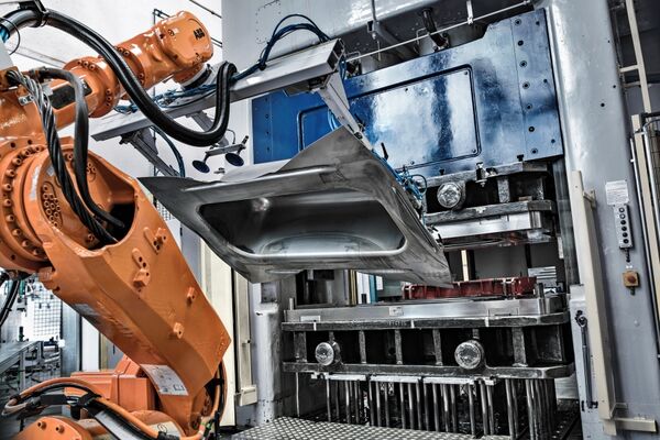 Der Roboter zieht eine tiefgepresste Wanne aus der Form.