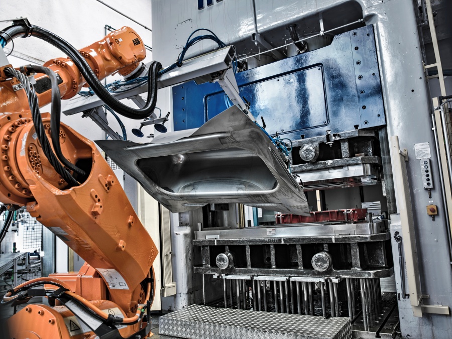 Der Roboter zieht eine tiefgepresste Wanne aus der Form.